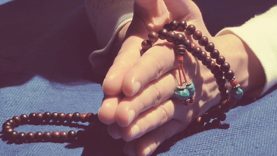 hands in Namaste holding a japamala